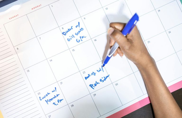 Uma criança regista tarefas num calendário, reforçando a importância da rotina infantil na organização do dia a dia e na gestão das atividades escolares.