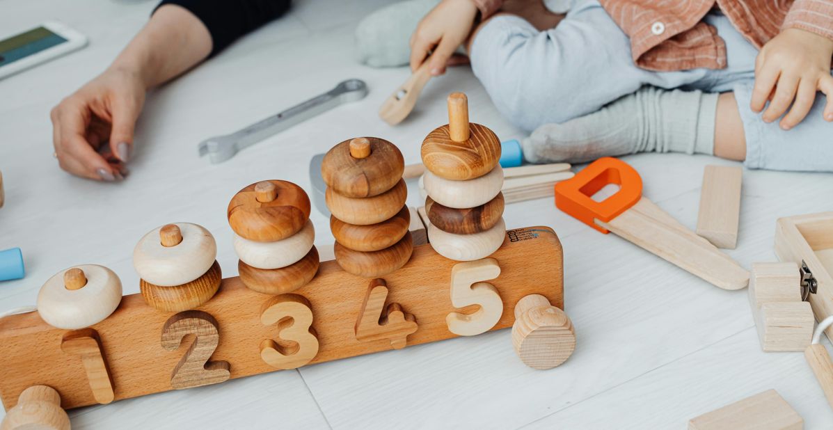 Uma criança manipula peças numeradas e empilha elementos, utilizando uma estratégia prática e visual que facilita a compreensão dos números, a sequência lógica e o desenvolvimento do raciocínio matemático através do brincar.