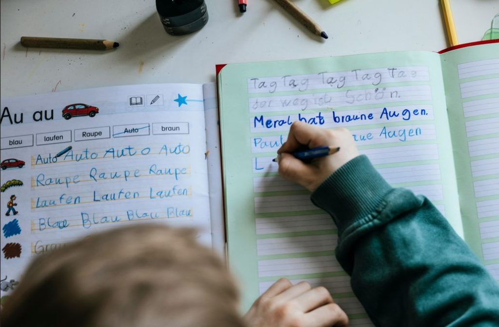 Uma criança pratica a escrita num caderno, evidenciando dificuldades típicas da disortografia, que afetam a correção ortográfica, a organização das palavras e a aplicação das regras da escrita.