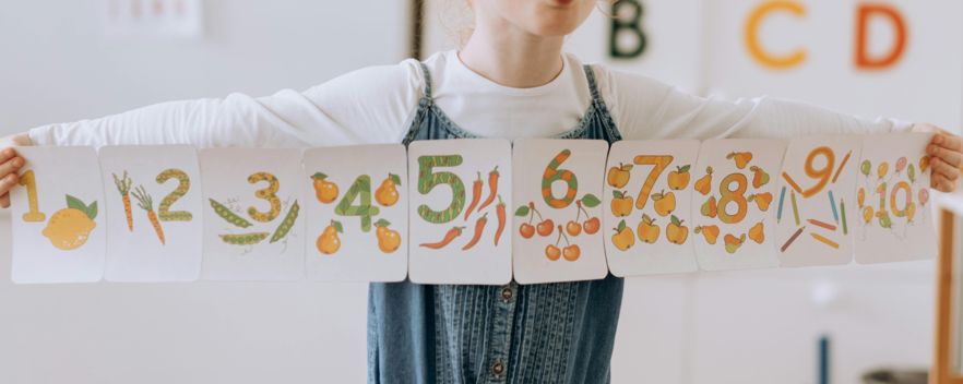 Uma criança utiliza cartões visuais com números e quantidades, uma estratégia eficaz para ajudar na discalculia, facilitando a associação entre número e quantidade de forma concreta e visual.